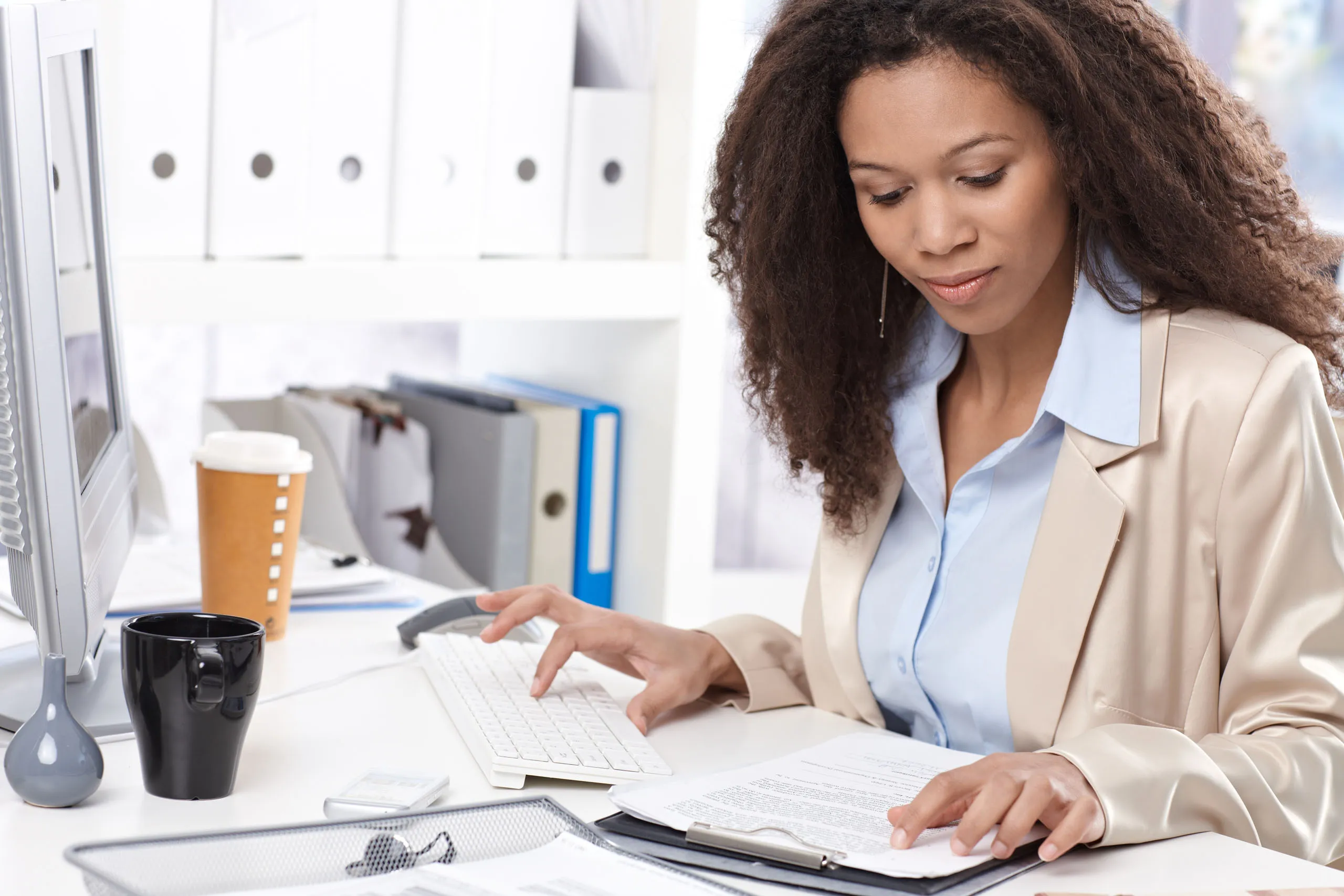An advocate at her desk, typing notes while reviewing case paperwork